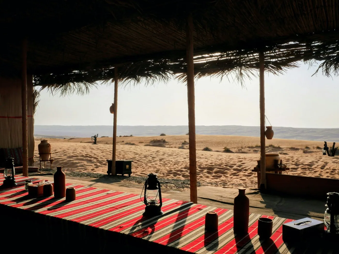 An intimate desert camp dining terrace overlooking open dunes in Oman