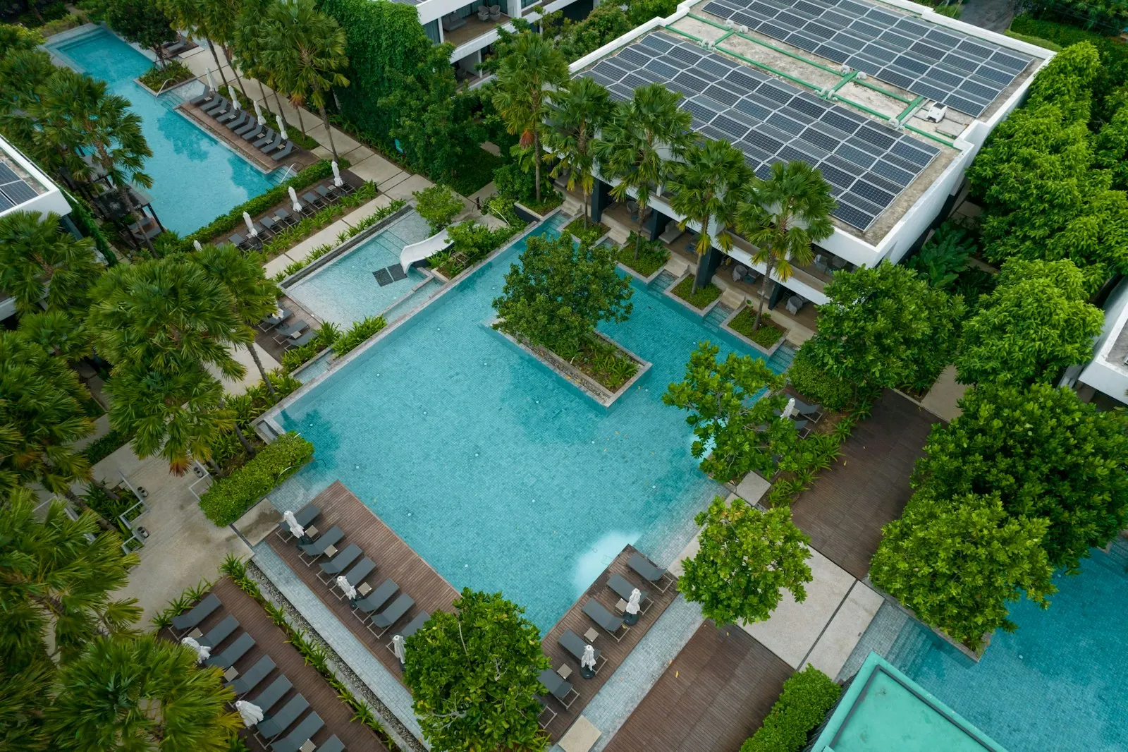Aerial view of a resort pool beside a roof-wide solar array